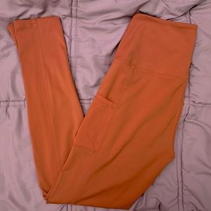 woman’s salmon colored mid waisted leggings with mesh pockets